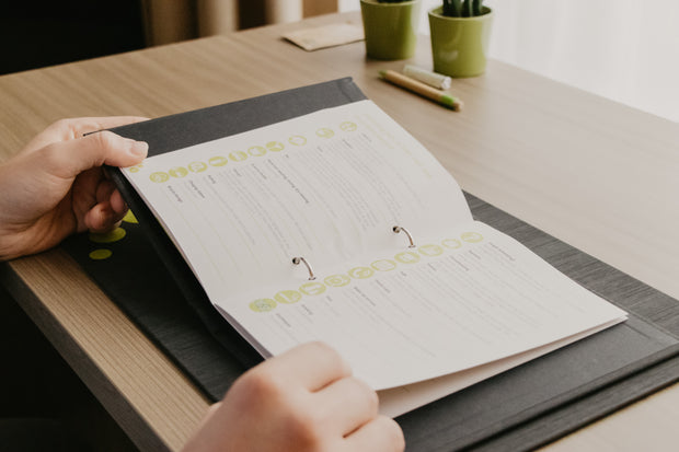 Planner met ringband op zwarte placemat op tafel in hotelkamer